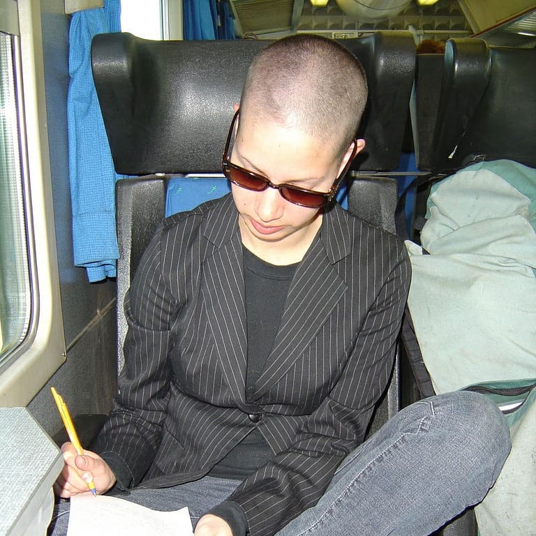 bald woman on a train writing in journal